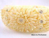 A vintage celluloid clamper bracelet - ivory-colored with carved flowers and rhinestones. Measures 7/8 inch wide and has an interior diameter of 2-1/4 inches. My wrist is 5-3/4 inches and it's a perfect fit. All rhinestones appear original and are in excellent condition. Silvertone hinge works beautifully. A beautiful bracelet with a winter-white color that's perfect for any season.