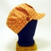 Orange engineer cap with buttoned band and geometric print
