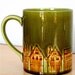 On Reserve for Amanda, who rocks. A beautiful green mug featuring a township. From 1968, maker HH.
