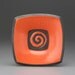 small orange\/poppy raku fired plate with spiral