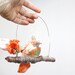 Lovebird Mobile perched for a KISS- fabric sculpture on brown yarn wrapped branch in blush pink, tangerine orange, green and rose