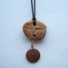 hand-carved avocado pit pendant necklace with bird, wood disc, on black woven cotton cord