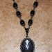 Black and pewter tone Victorian style 18 inch necklace with clasp and black oval charm with net look over clear glass