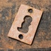 Vintage primitive small brass key hole escutcheon.