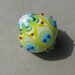 Handmade lampwork glass bead in yellow, different shades of green, blue and white by Flamejewels