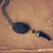 imala. a black and gold tusk necklace.
