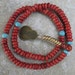 Coral mala with turquoise accents and brass charm