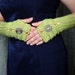 Light olive green fingerless gloves with decorative elements.