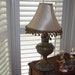 Vintage, repurposed oil lamp with silk shade adorned with bronze and verdigris ball fringe.