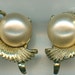 Vintage gold toned metal clip on earrings in a shell style with a large faux pearl