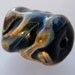 Lampwork focal bead in swirls of textured colors of blues, browns,blacks, and lavenders