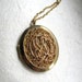 Oversized vintage gold tone oval locket, with filigree embellishment on long chain, by Park Lane