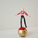 Brass acrobat miniature sculpture, enameled, red black acrobat on a moving brass ball
