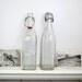 Vintage glass bottle set........ porcelain stoppers....wire holders....industrial....Italy