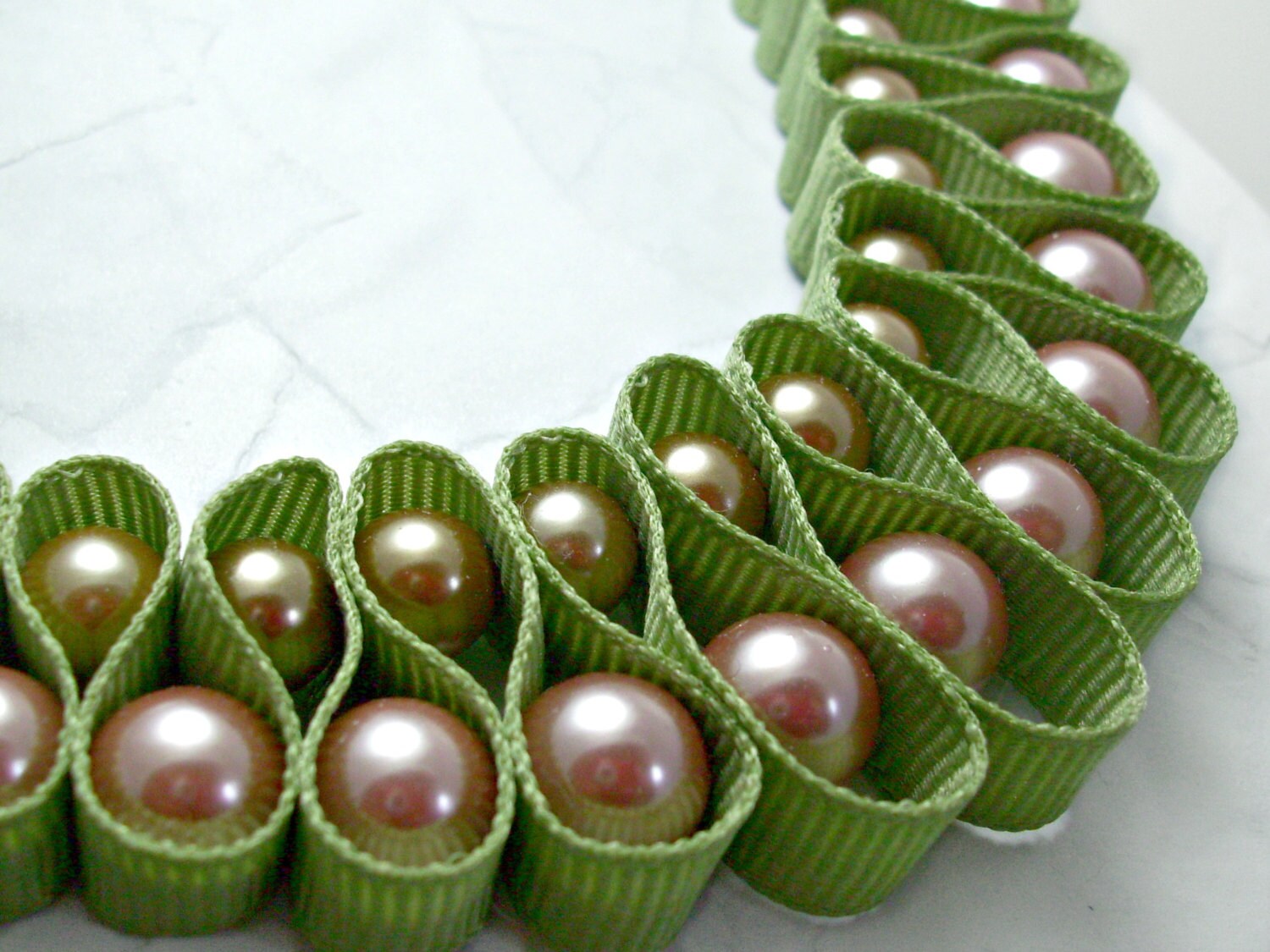 Light green ribbon looped pearl necklace. Gold pearls and