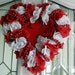 Valentine's Day Heart shaped wreath with red and white roses, a cupid in the center and shiny red bead garland