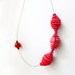 geometric minimal necklace with red circles and a red dot - contemporary jewelry