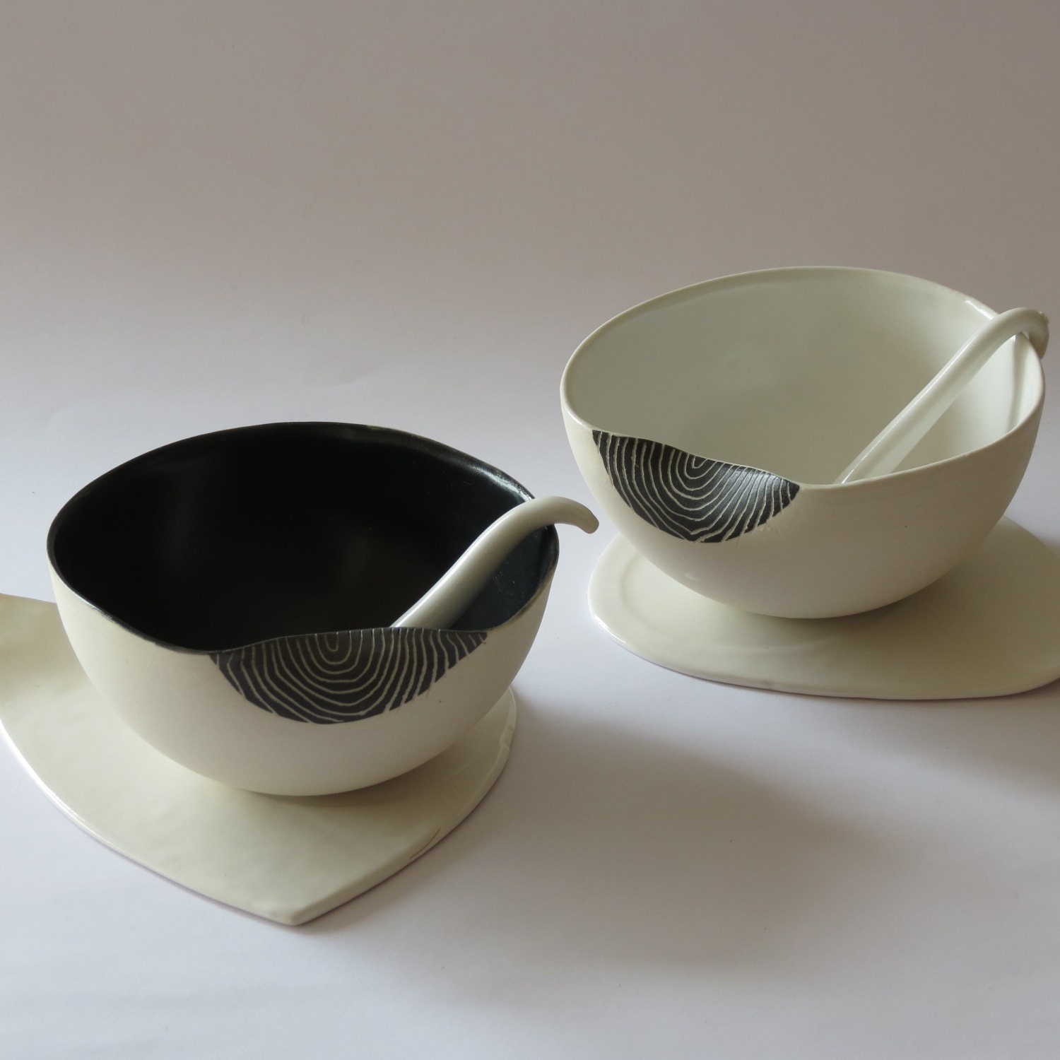 A set of two black and white serving dishes with triangular saucers