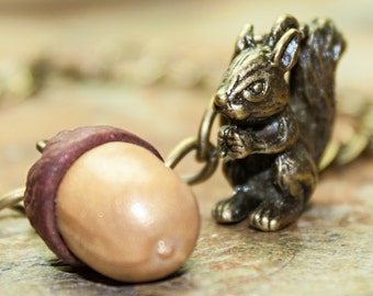 British Red Squirrel Contemplates Fired Clay Acorn On a Bronzed Chain Bracelet (Sciurus vulgaris)
