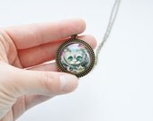 IN WONDERLAND Round pendant made of brass with the image of the Cheshire Cat under glass