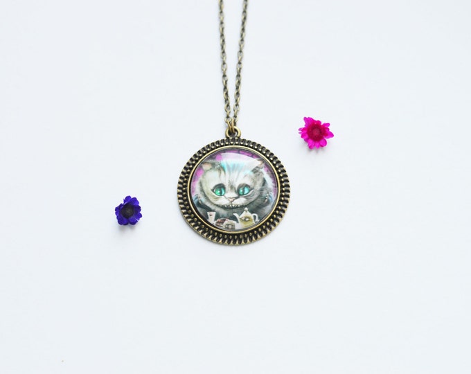 IN WONDERLAND Round pendant made of brass with the image of the Cheshire Cat under glass