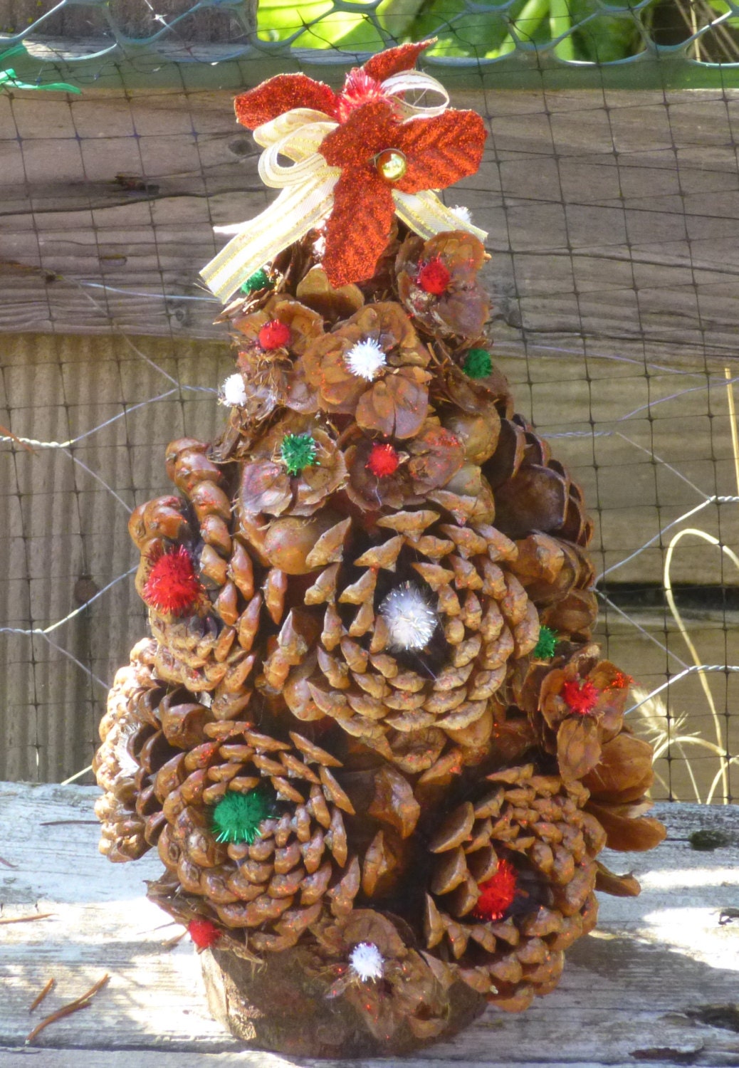 Decorated Pine cone rosette holiday tree with acorns and fir cone flowers This tree is decorated with traditional colors