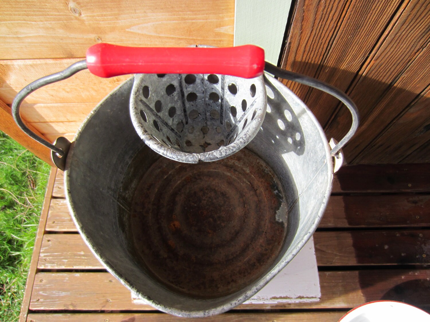 Vintage metal mop bucket with red handle and mop top insert.