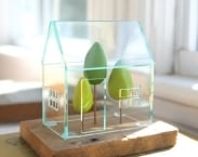 Miniature greenhouse structure - small acrylics architecture around green trees - glass house -look solarium