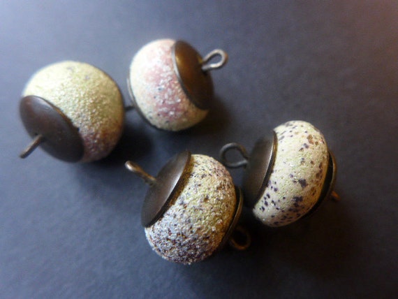 Concrete. 4 pale green polymer clay artisan doughnut bead links with pitted speckles and dark brass caps.