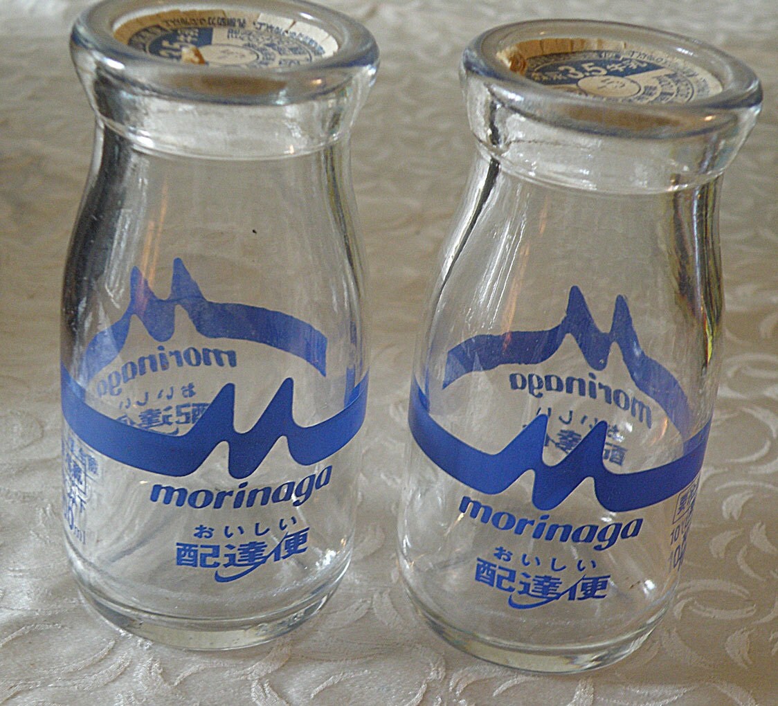 two small japanese milk bottles with paper lids