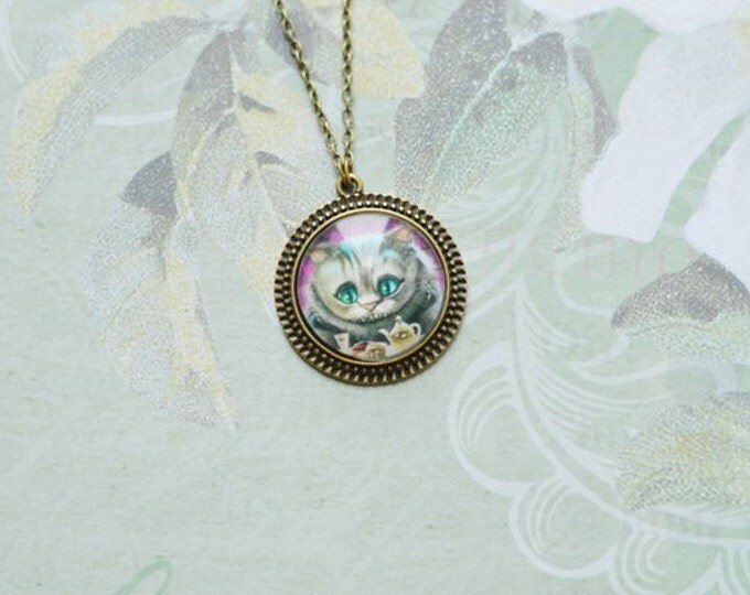 IN WONDERLAND Round pendant made of brass with the image of the Cheshire Cat under glass