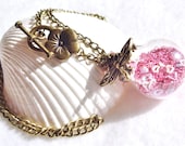 Round glass orb necklace filled with delicate pink fiber beads, hearts and bronze chain