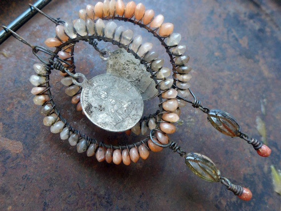 A Tattered Prayer. Shaded moonstone, rhinestones and religious medals. Peach and grey assemblage earrings.