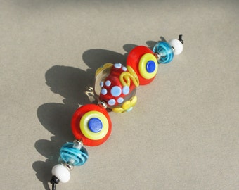 Handmade lampwork glass beadset in vibrant colors like red, blue, yellow and green by Flamejewels.