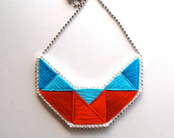Embroidered geometric statement bib necklace in reds and blues on cream muslin with felt backing on silver ball chain