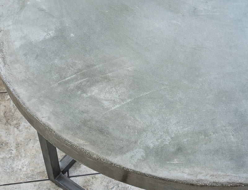 Handcrafted concrete table top with welded steel legs.