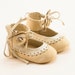 Beige leather baby shoes made from braided leather and embellished with a rose
