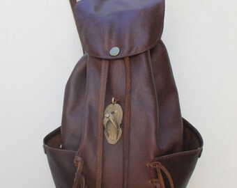 Handmade molasses bovine leather backpack with two side pockets and fringing. Lining and inside zip