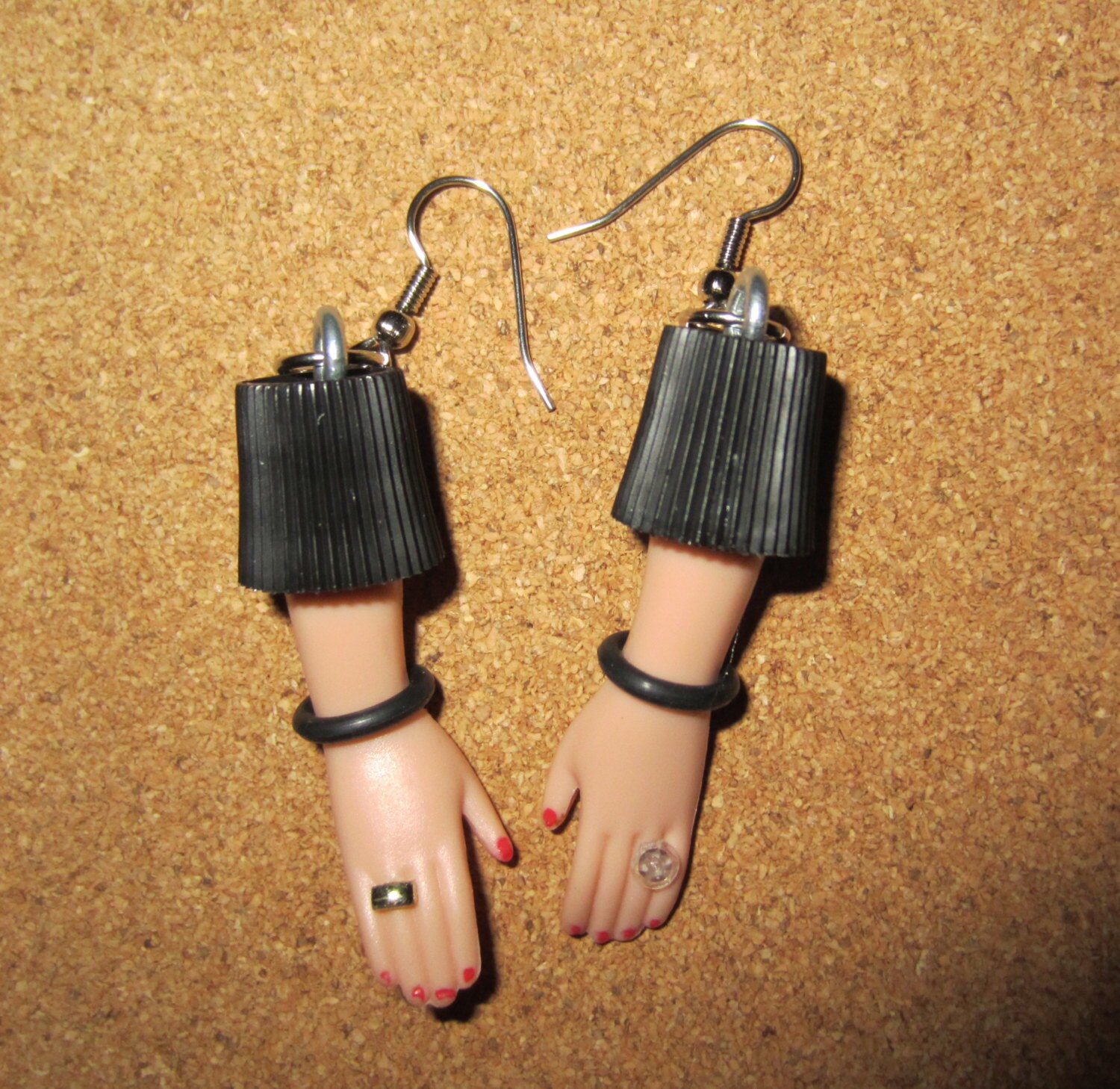Barbie doll hand earrings with red polish and black bracelets