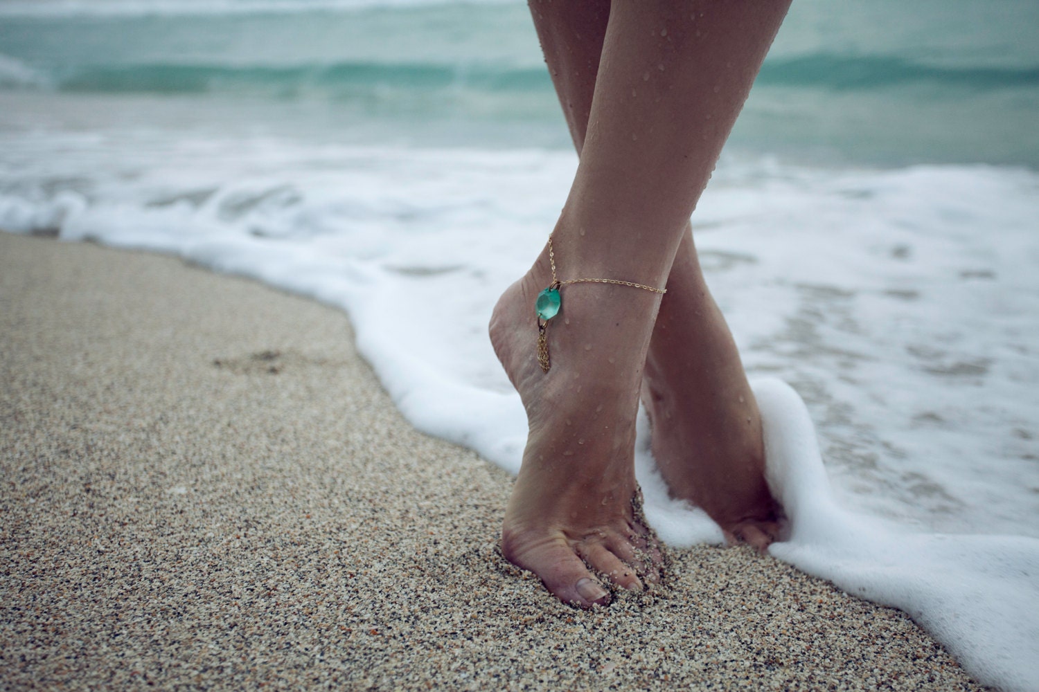 Ноги в браслете босиком на песке