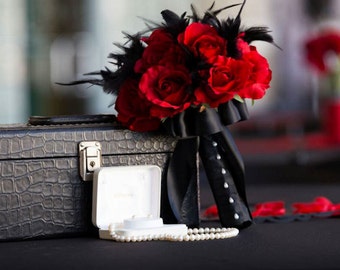 Black feather and rich red rose bouquet and boutonniere set