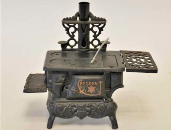 Vintage cast iron miniature stove with pots.