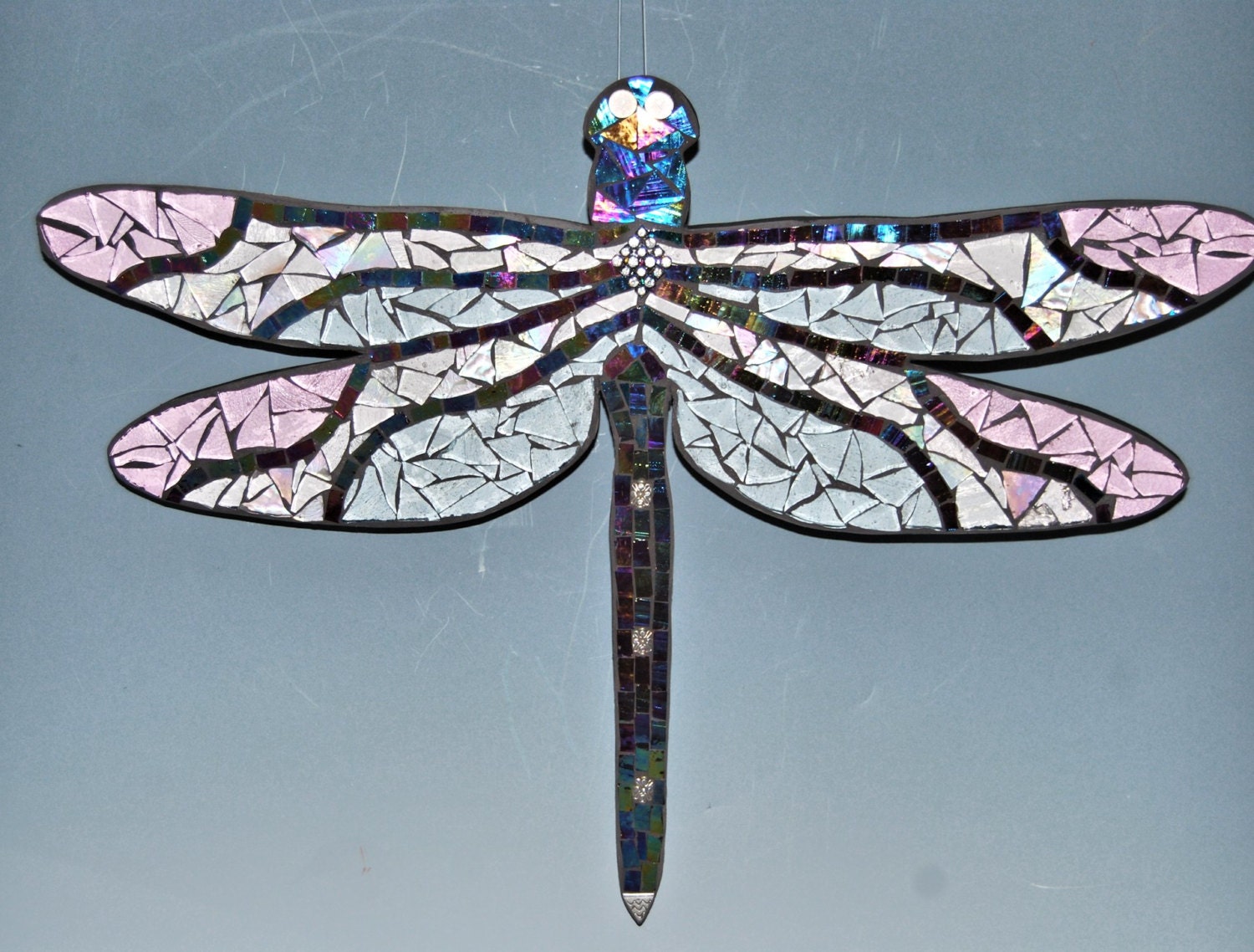 Mosaic dragonfly made with stained glass on wood surface to
