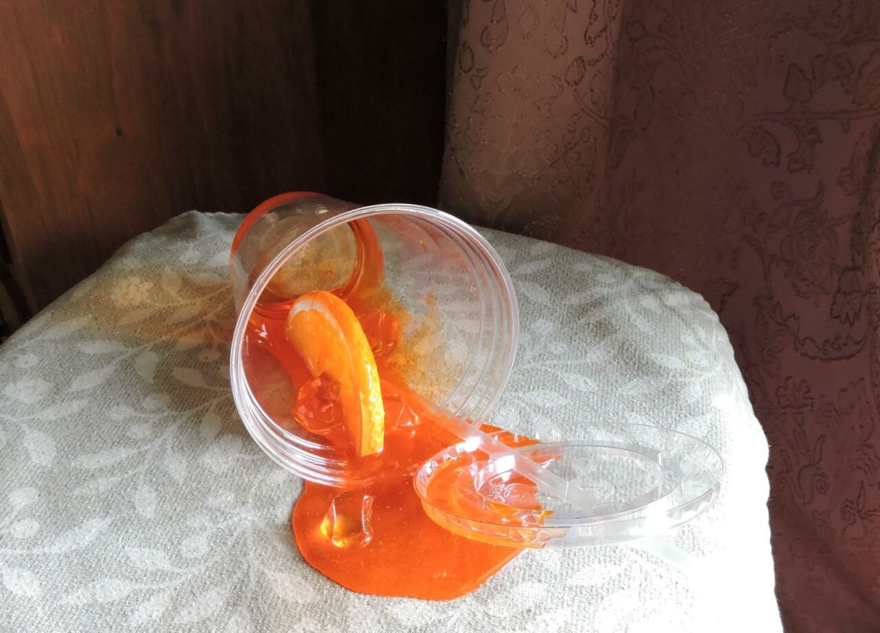 Fake Spilled Orange Soda in a Plastic Cup With Orange Slice