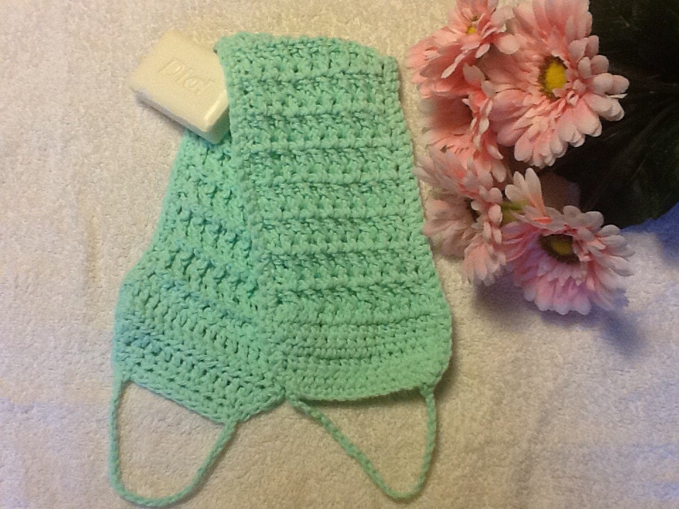 A green crochet massaging back scrubber made out by CrochetJoy2015