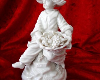 A Royal Nymphenburg Blanc de Chine figurine of a Fruit Seller sitting, model No.1173b 6 with a 1960 back stamp