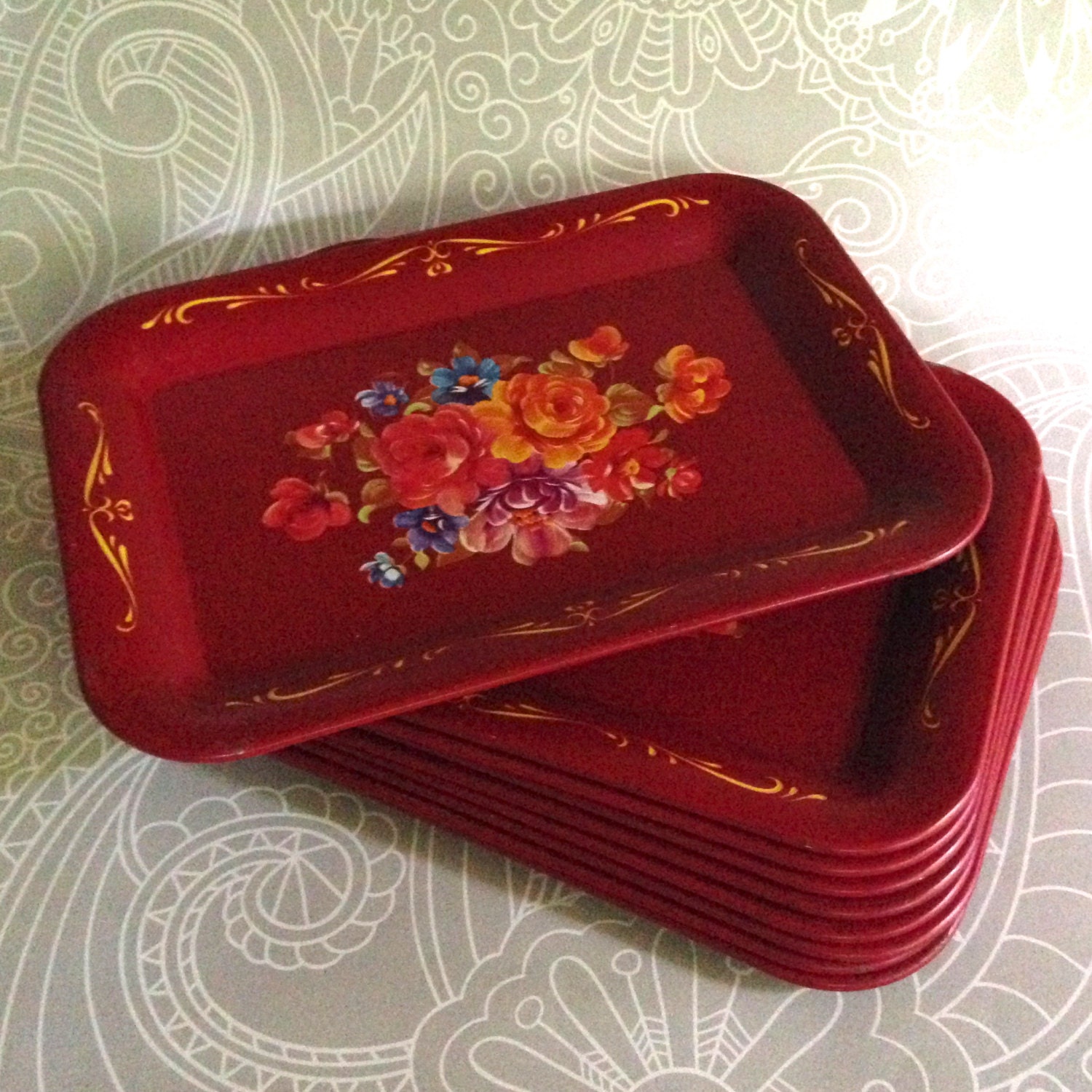 Set of eight small snack trays with painted flowers on red metal from