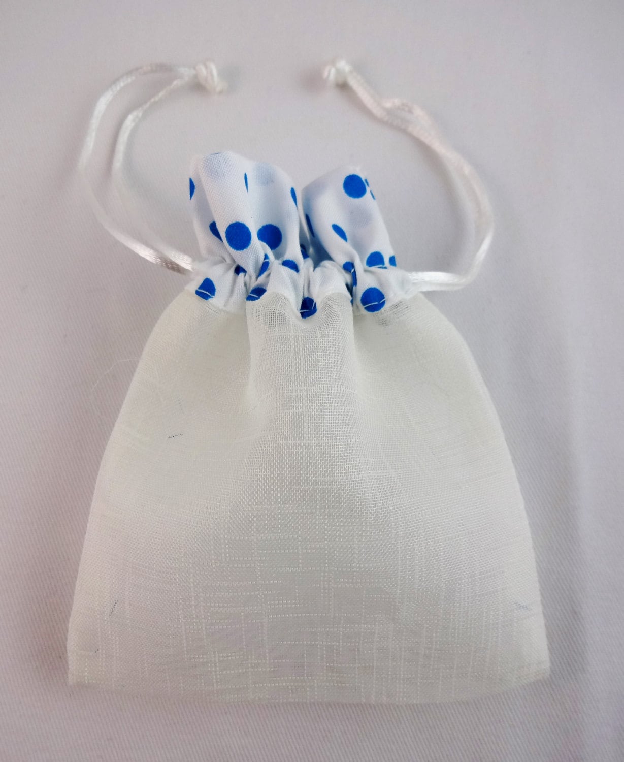 Set of six white see through fabric drawstring bags with blue