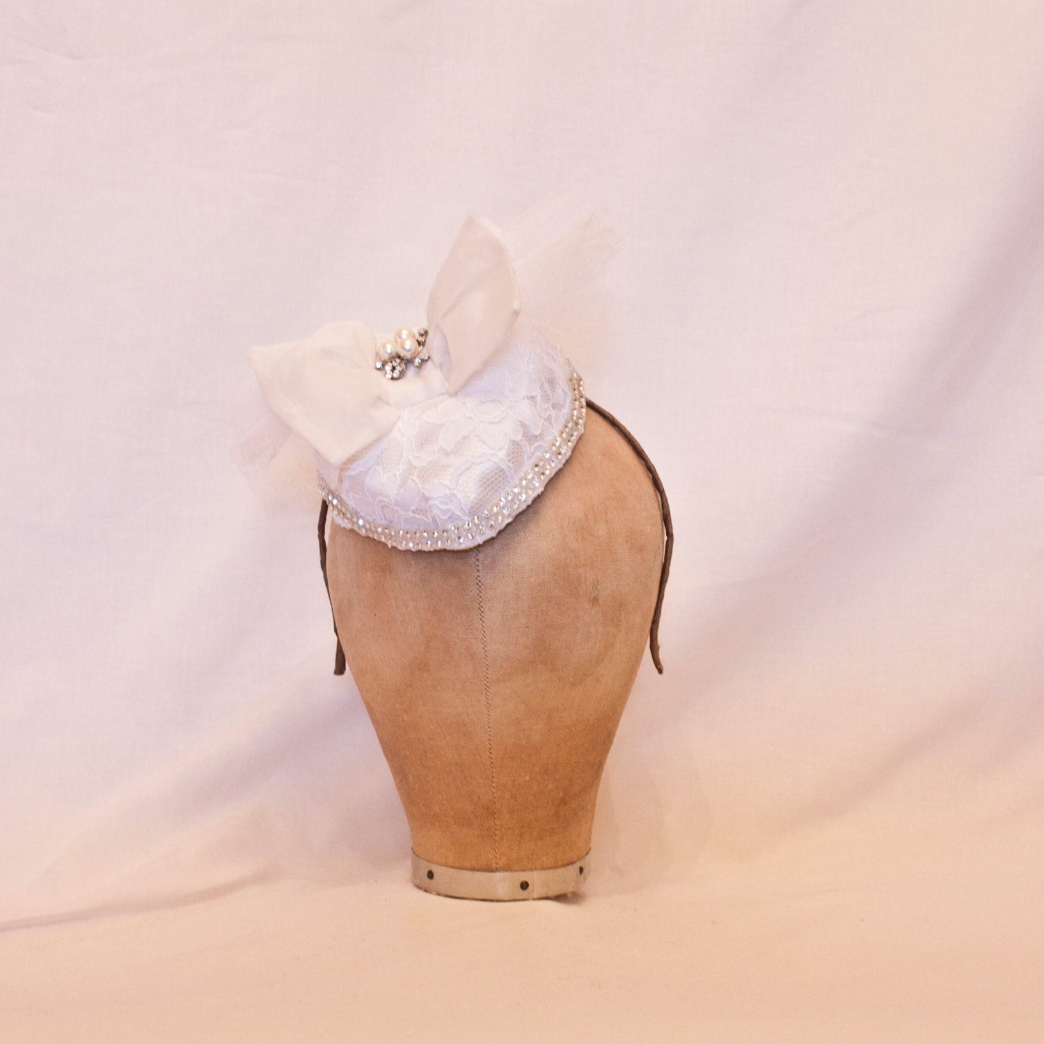 Handmade white heart shaped hat with a white lace overlay and bow and jewel detailing