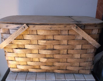 Rustic picnic basket made with woven split oak. Has a hinged lid and measures 19 inches long 11 inches wide and 11 inches deep